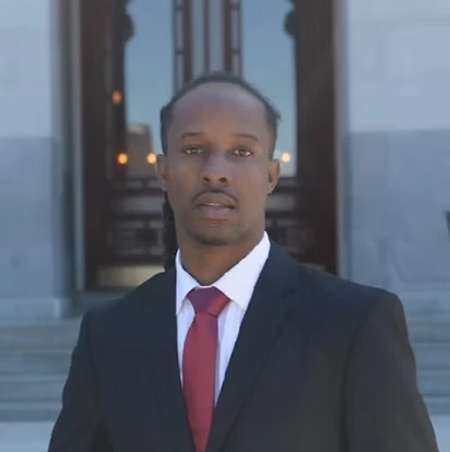 Portrait of Tremmel Watson in a dark suit and red tie